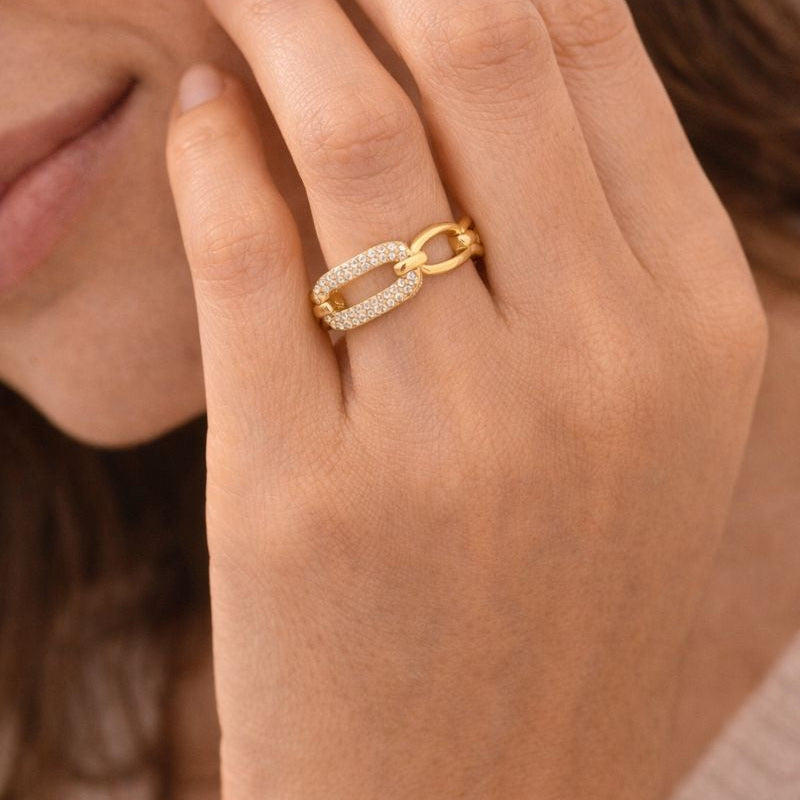 Close-up of a hand wearing a gold ring with a blurred background