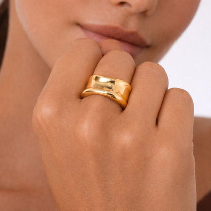 Close-up of a hand wearing a gold ring with a blurred background