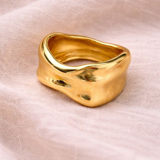 Gold ring on a soft pink fabric background